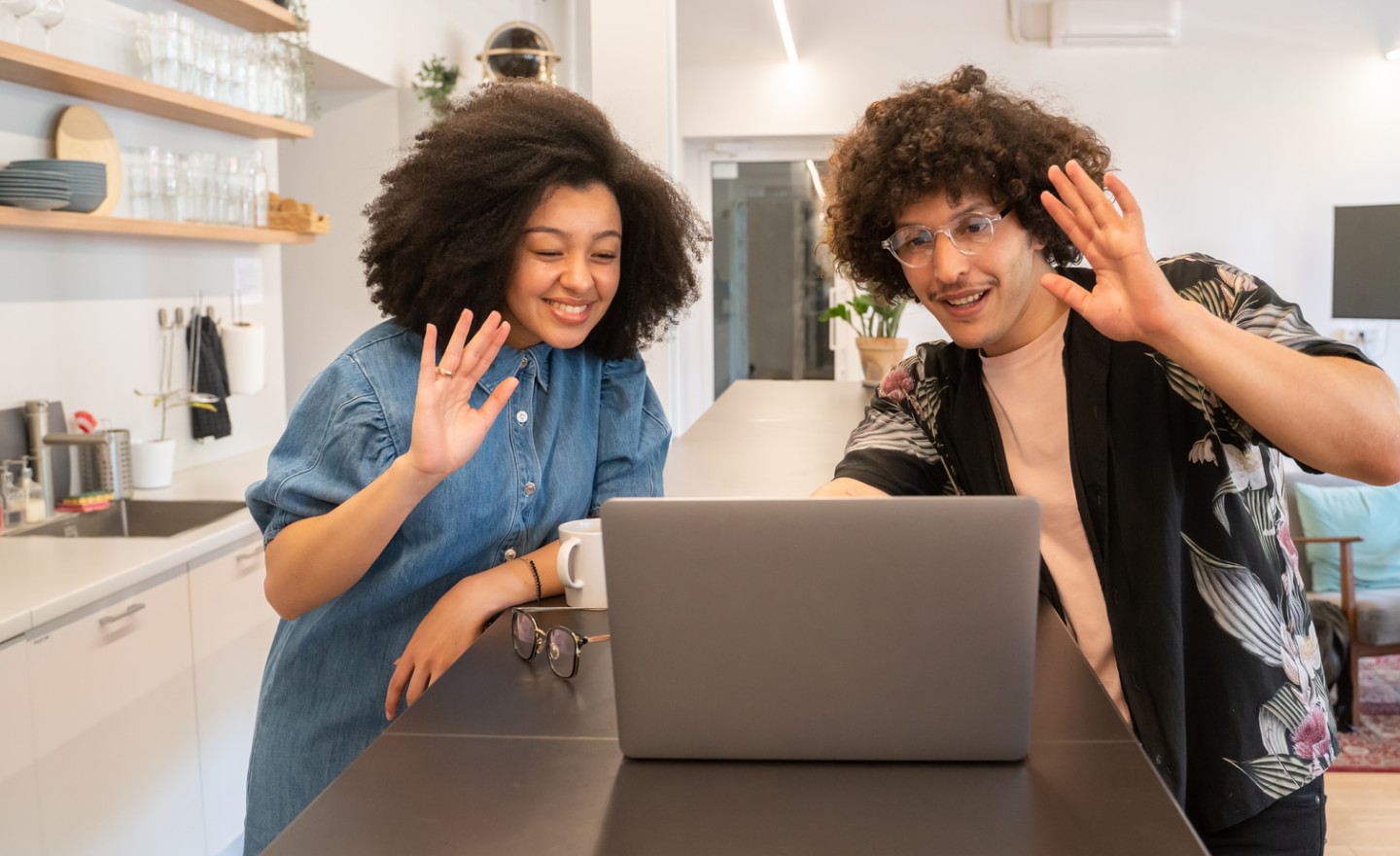 Man and woman attending video call waving