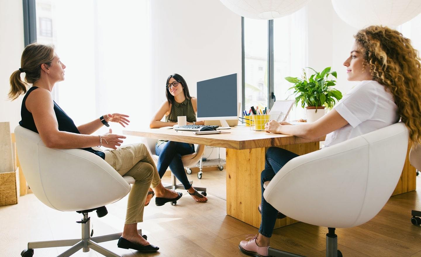 Three women gathered around a desk