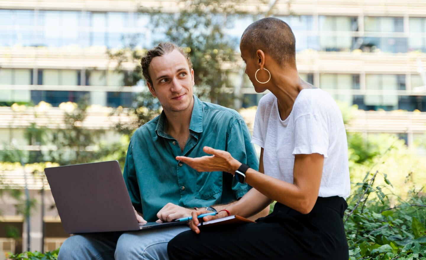 Two coworkers working on laptop outside