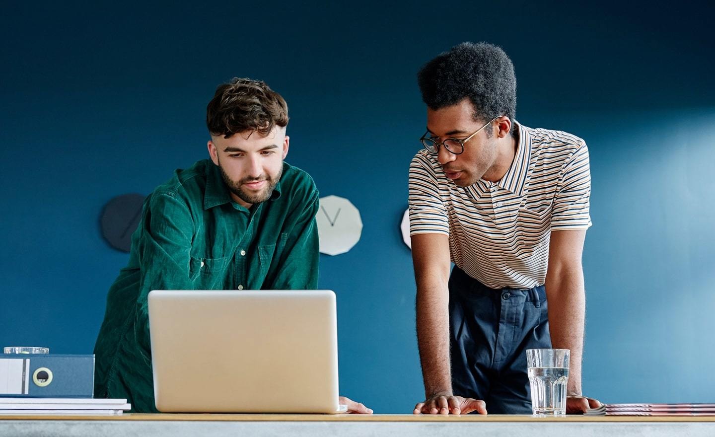 Two men standing in front of a blue wall