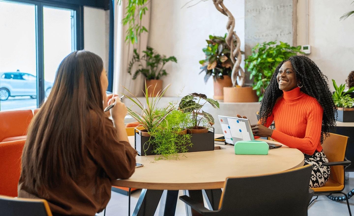 Two women sitting at work table chatting