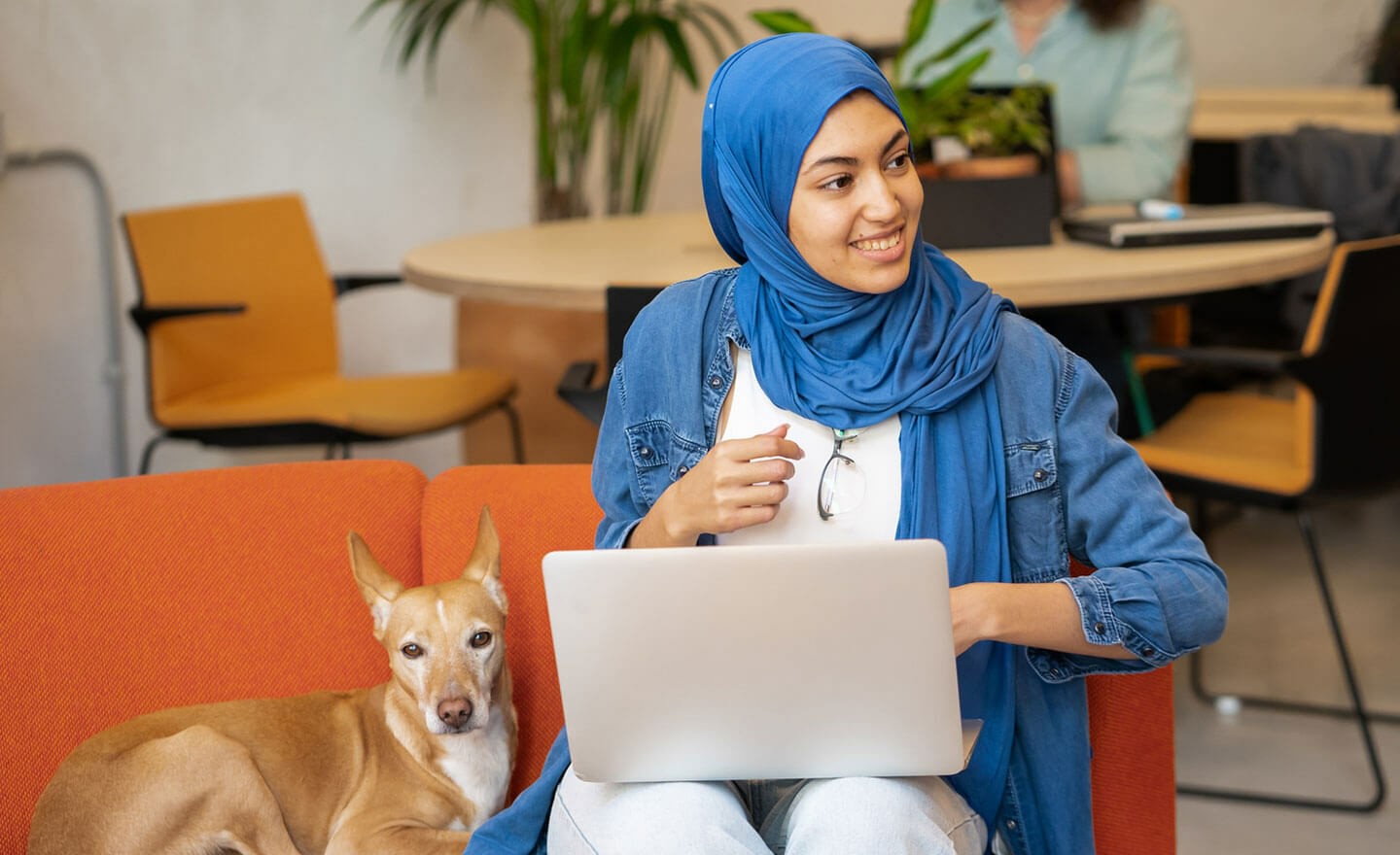 Woman working on laptop in coworking space blue head scarf