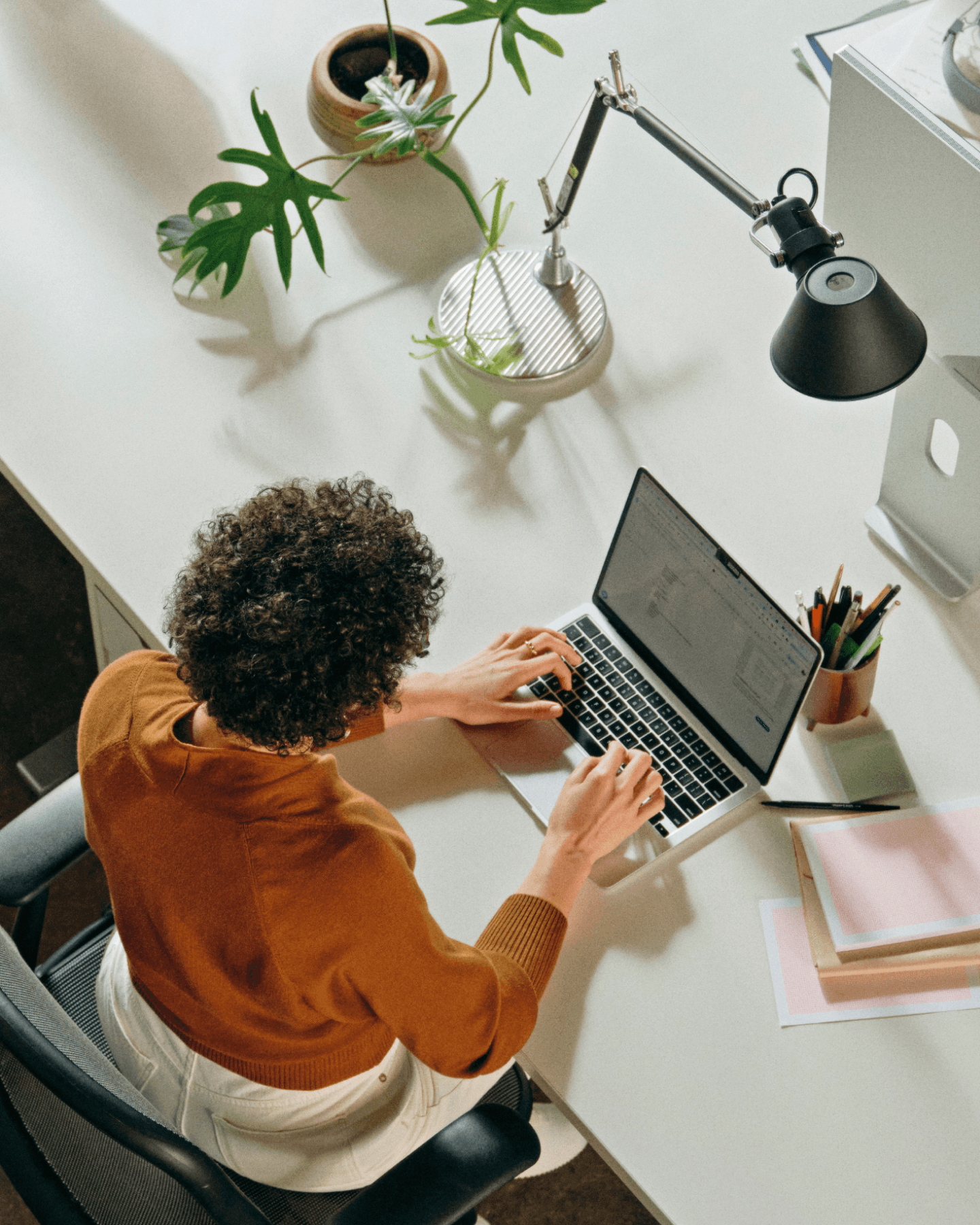 Aerial photo of office worker in brown shirt working at a communal desk