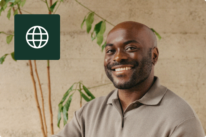 Man posing and smiling in a casual office with globe icon