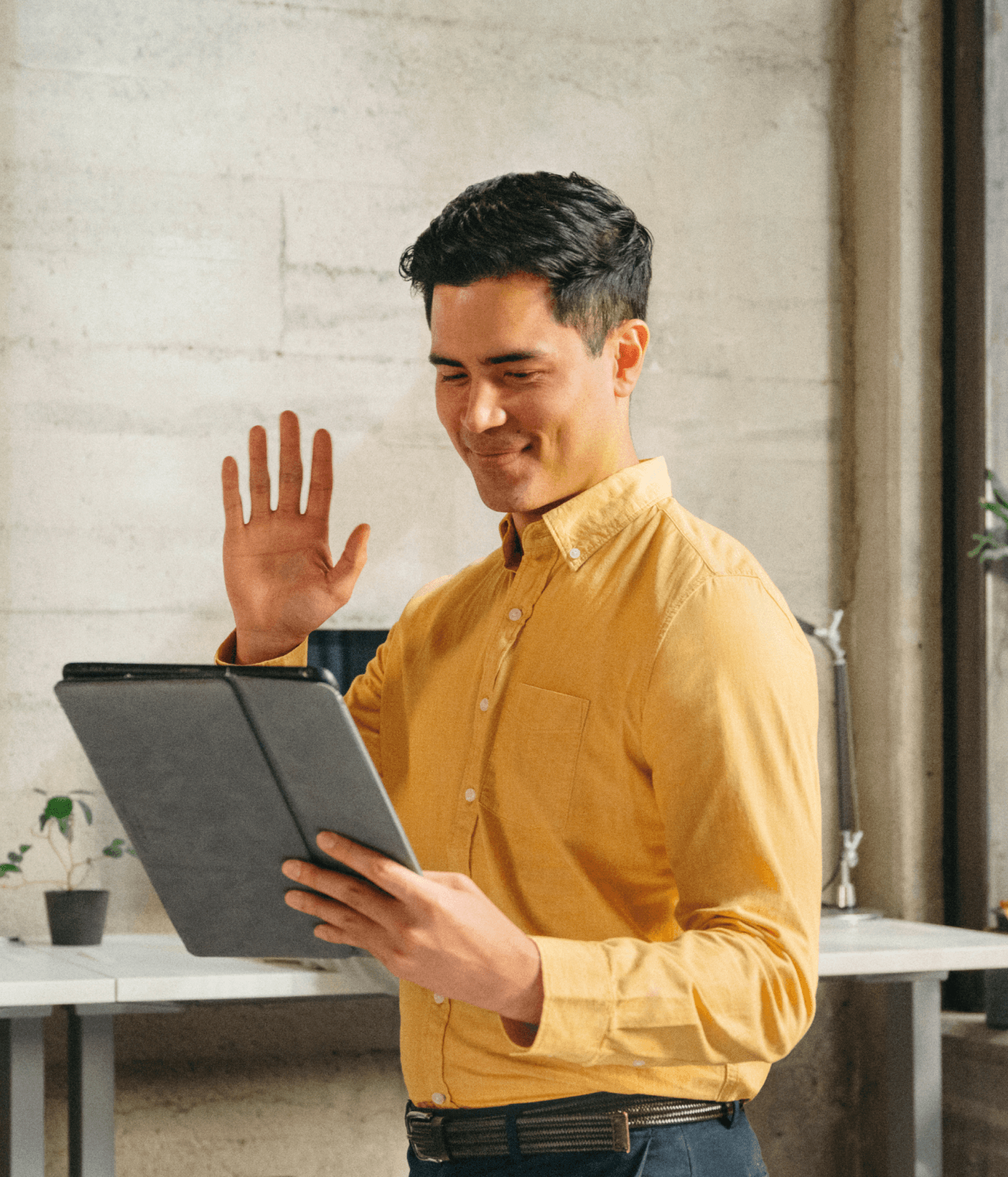 Office worker in yellow shirt waving at person on video chat