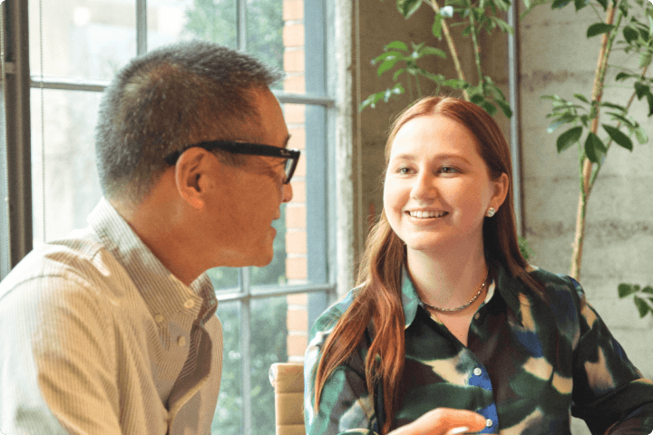 Two coworkers chatting in a conference room while seated