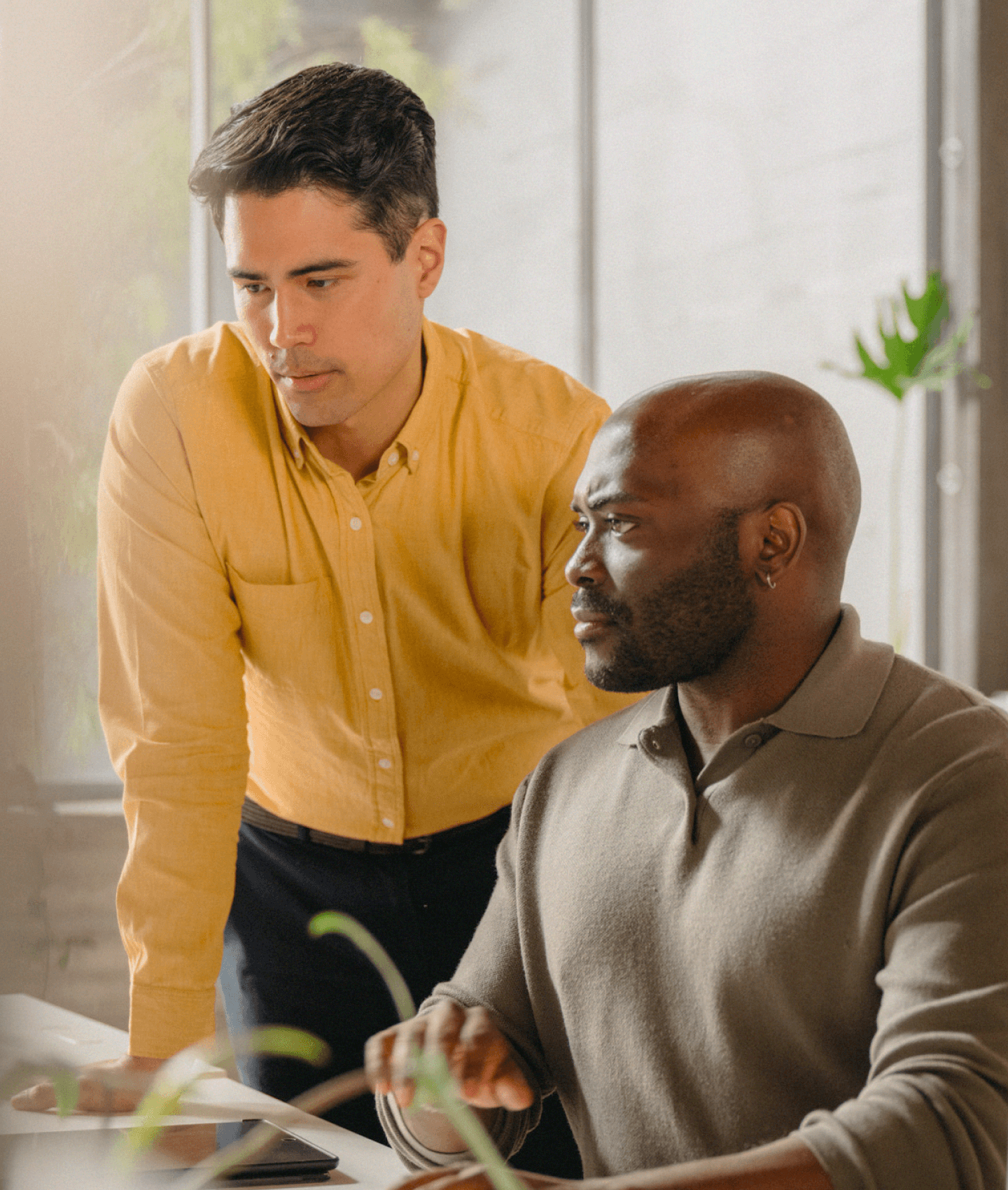 Two coworkers reviewing content on a computer in warmly lit office