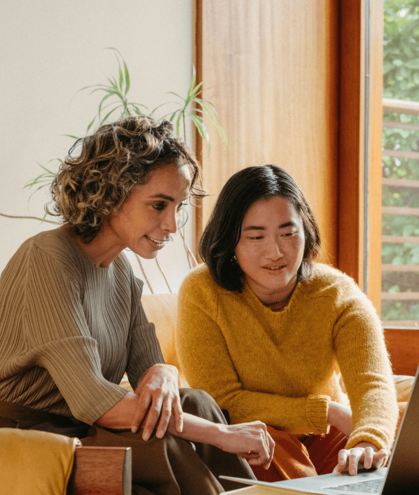 Two women in warm toned casual office collaborating