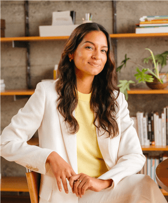 Woman in white suit posing in office environment with bookshelf