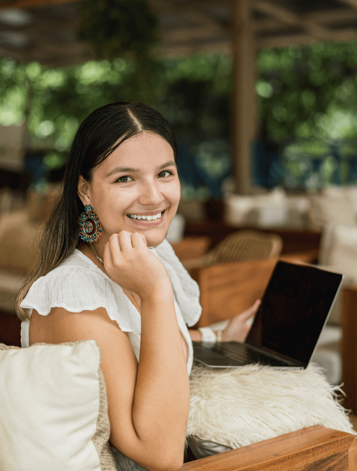 Woman smiling outdoors with laptop