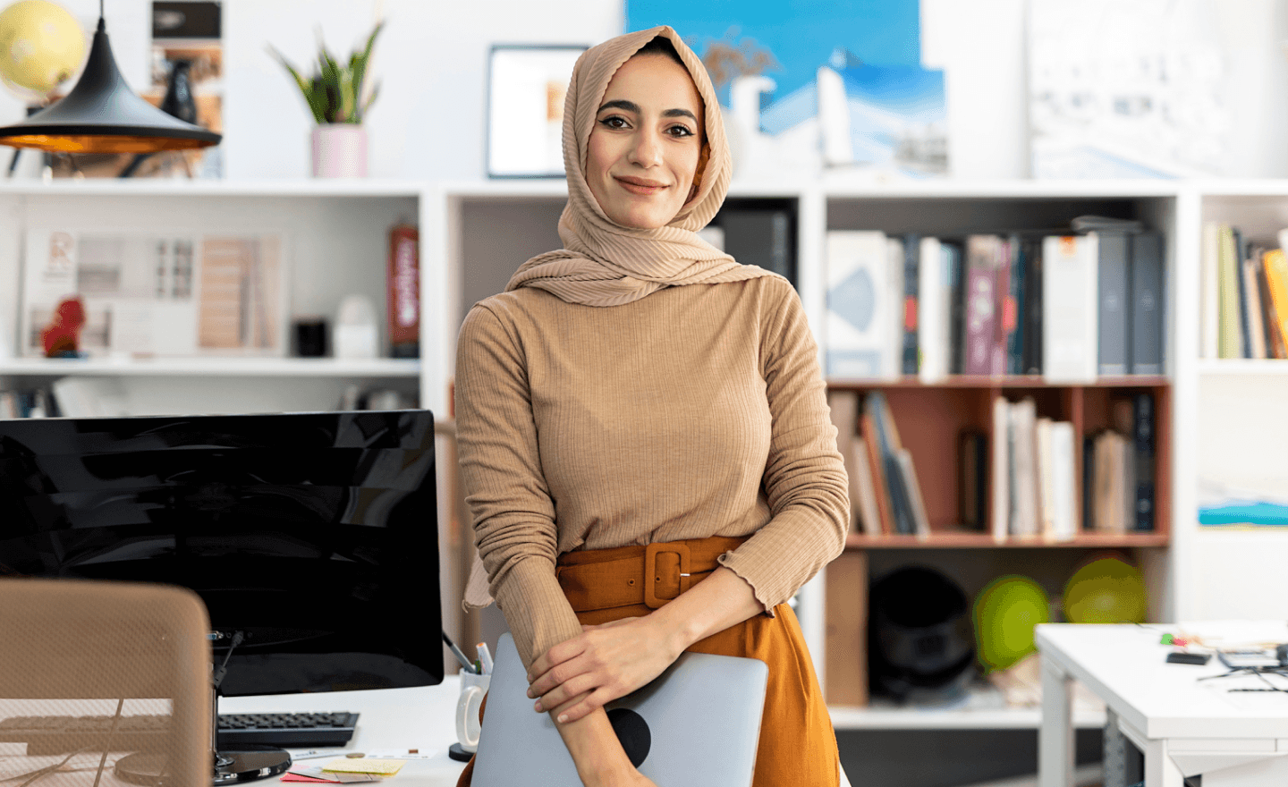 Woman wearing headwrap smiling while holding laptop